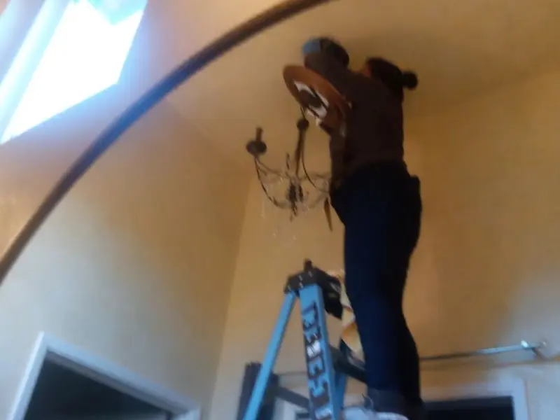 Electrician installing a chandelier in a Atwater residence